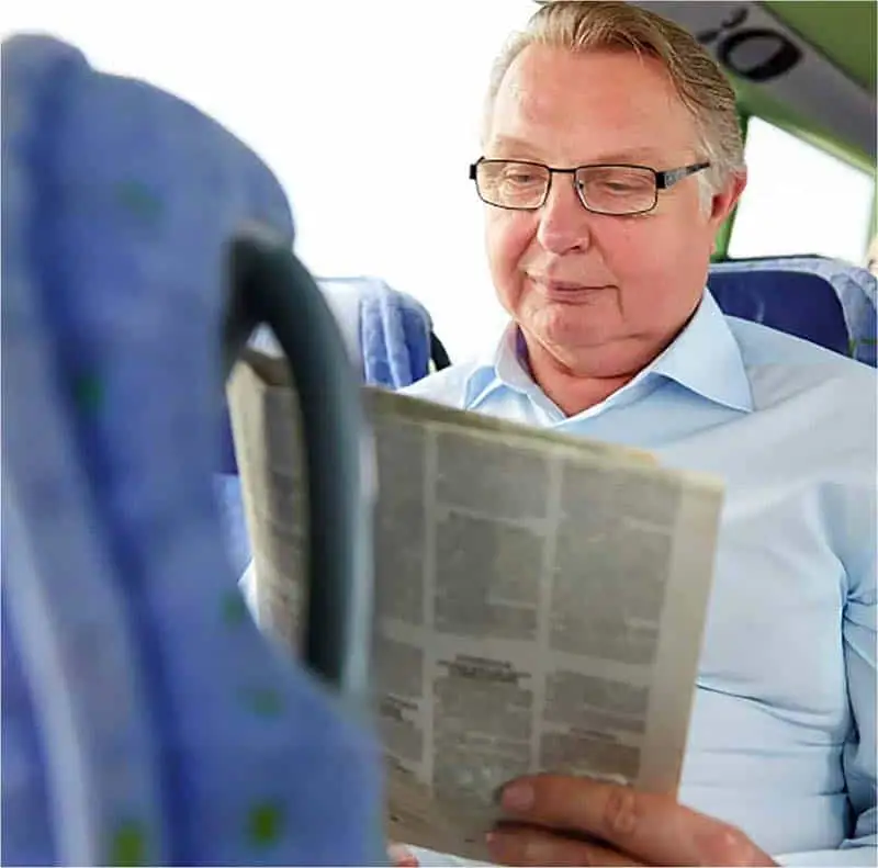 Man sitting on bus reading newspaper