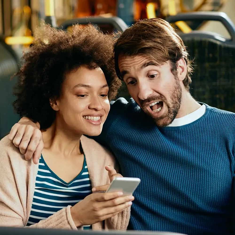 Couple smiling while reviewing phone