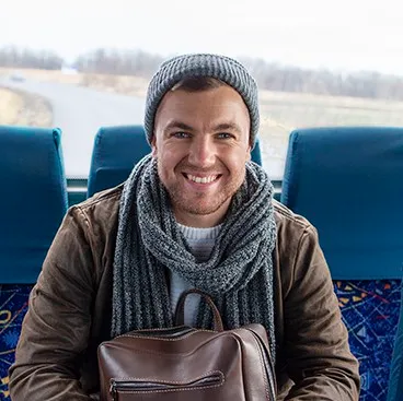 Man waiting at transit stop smiling